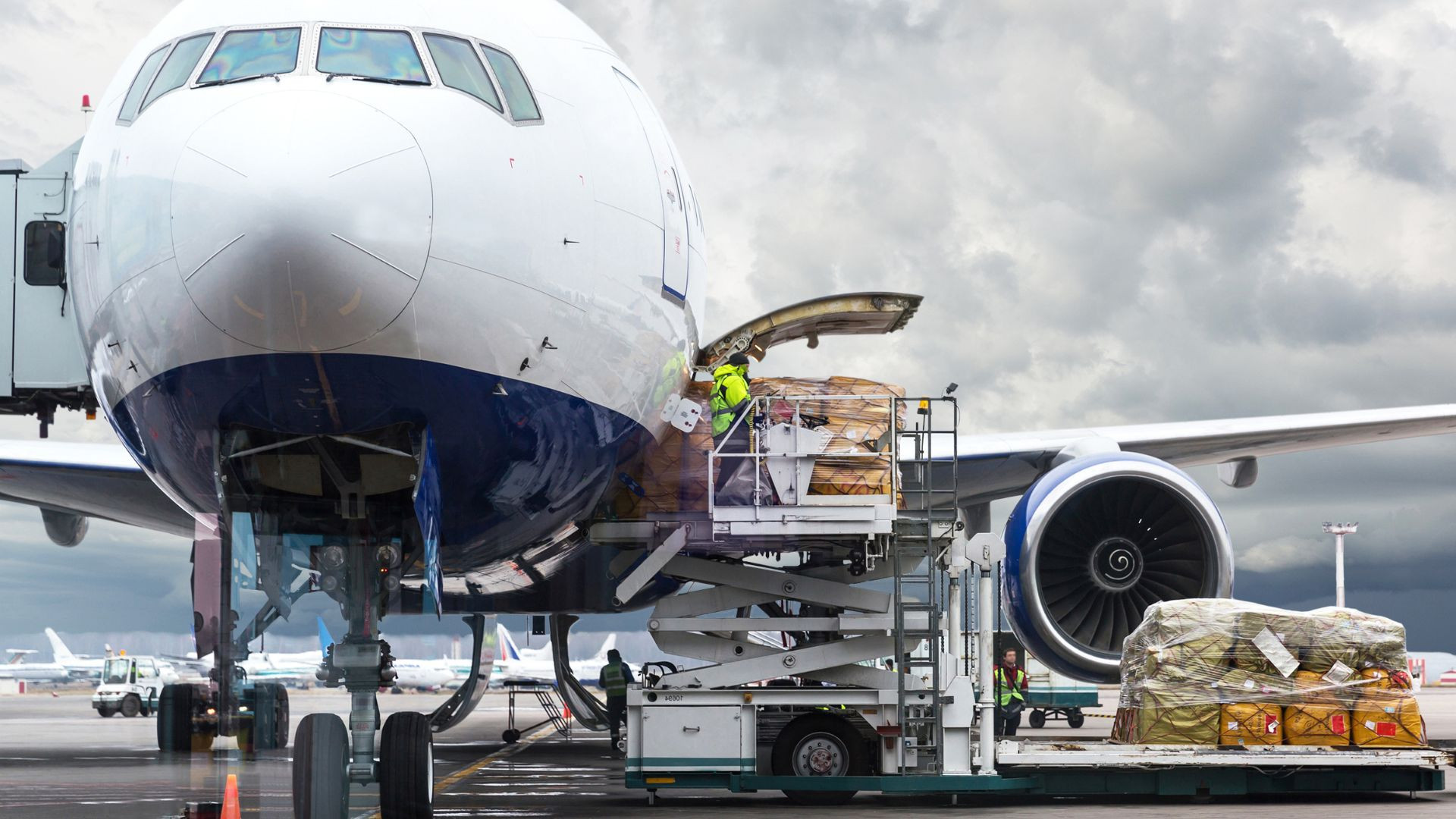 Palletised air cargo being loaded into an aircraft using an airport cargo lift.
