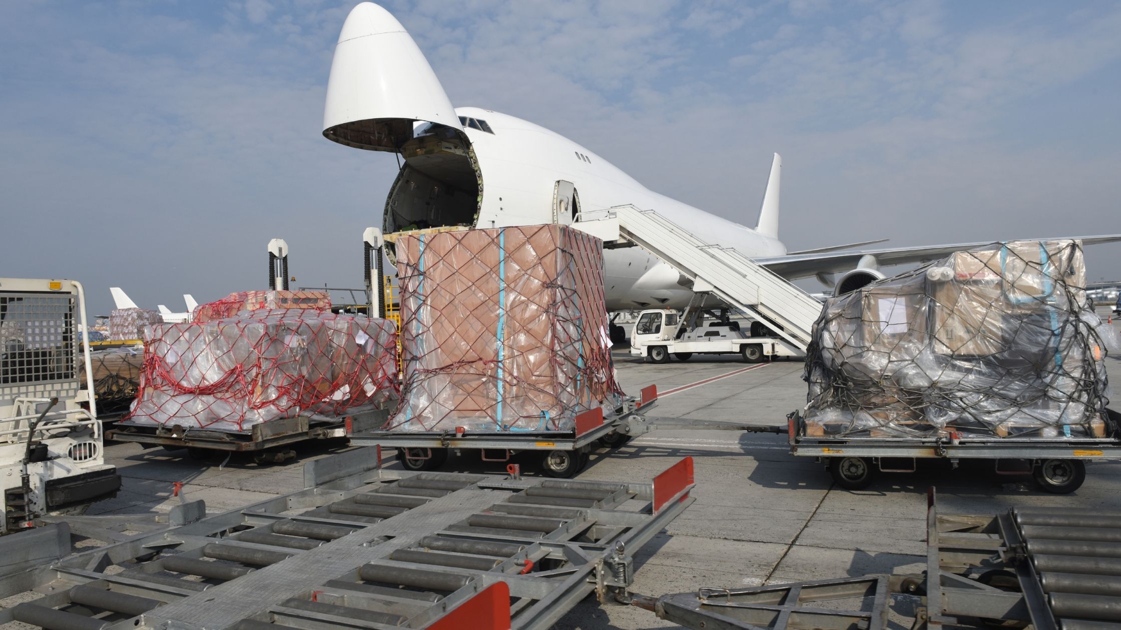 Luftfrachtpaletten werden neben einem Frachtflugzeug für ein internationales Luftfrachtangebot abgefertigt